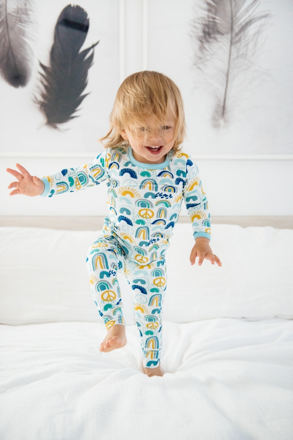 Toddler jumping on bed in Clover Baby & Kids pajamas celebrating Rainbow Baby, IVF, and Infertility