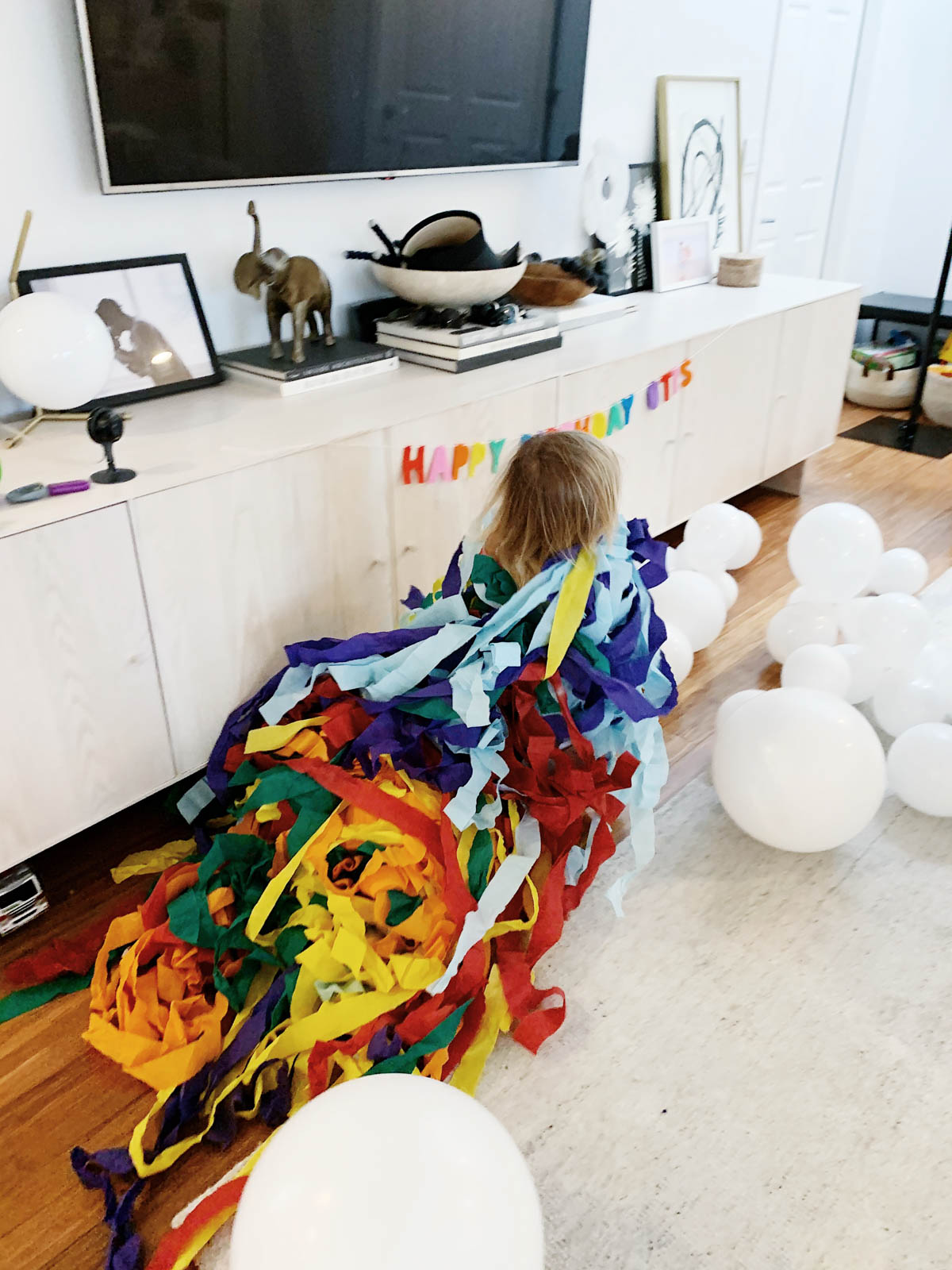 Toddler running with streamers from Trolls theme birthday