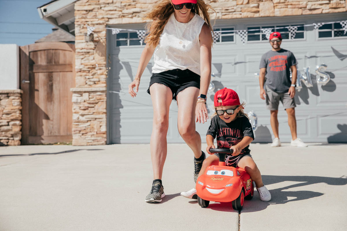Mom chasing toddler and Ride on Lightning McQueen Car Toy at Disney Pixar Cars themed birthday