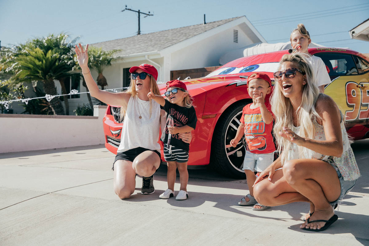 Moms and toddlers posing with Lightning McQueen Impersonator Car at Disney Pixar Cars themed birthday