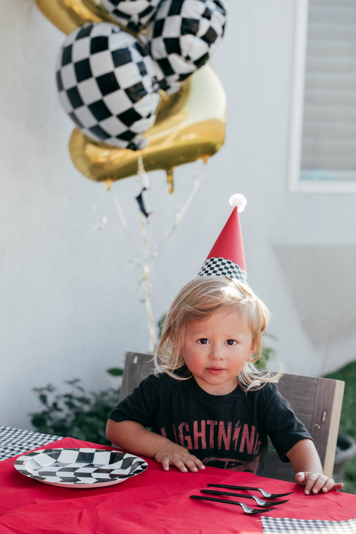 Birthday boy with custom race car party hat and race car theme party decorations at Disney Pixar Cars themed birthday