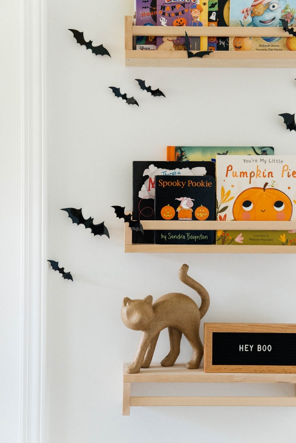 Best Halloween Books for Toddlers styled on wooden shelves with bat wall decals