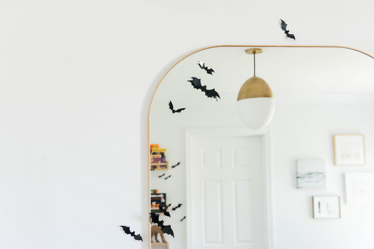 Best Halloween Books for Toddlers styled on wooden shelves with bat wall decals in nursery with modern mirror