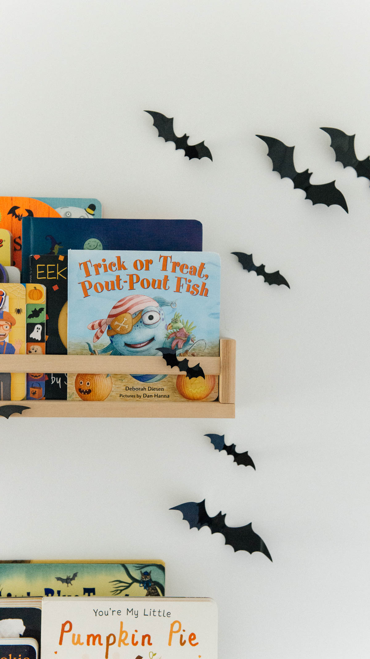 Best Halloween Books for Toddlers styled on wooden shelves with bat wall decals