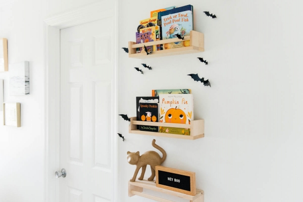 Best Halloween Books for Toddlers styled on wooden shelves with bat wall decals in nursery