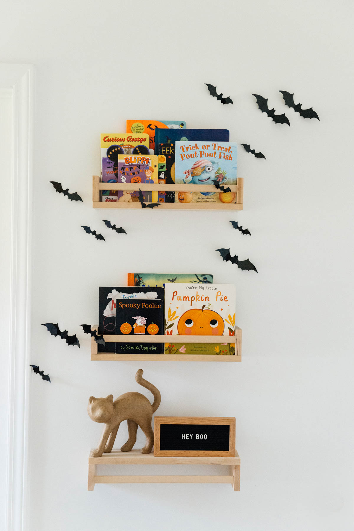 Best Halloween Books for Toddlers styled on wooden shelves with bat wall decals in nursery