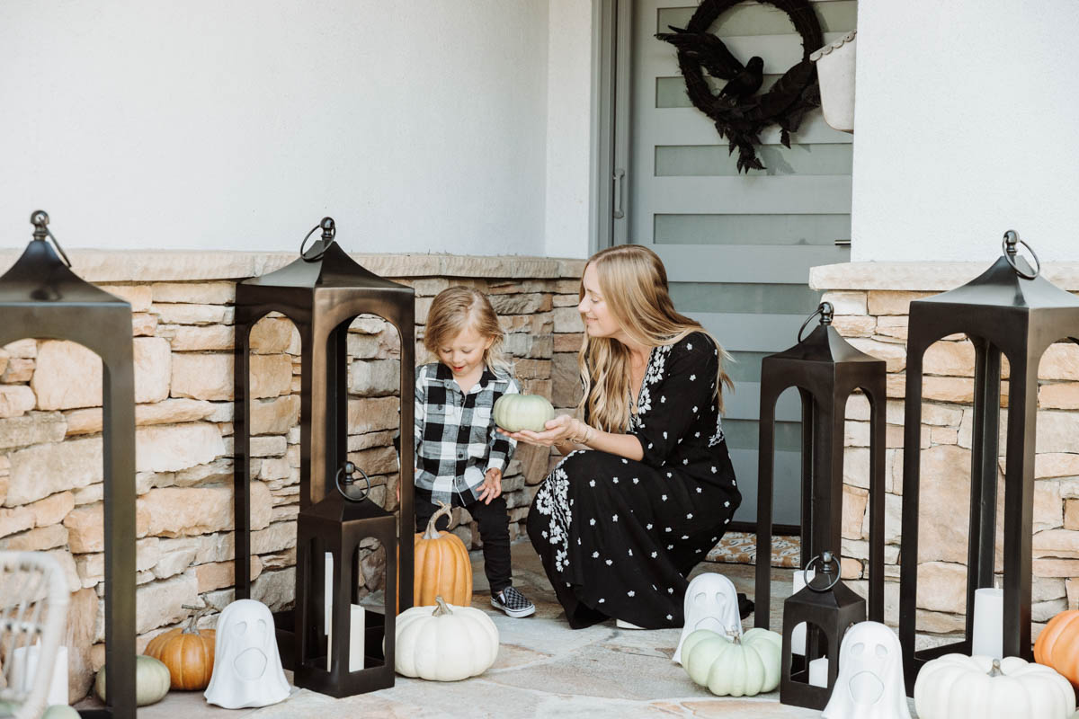 Fall & Halloween Decor For Patio & Yard with Lanterns, faux pumpkins, crow wreath and LED ghosts with toddler holding faux pumpkin