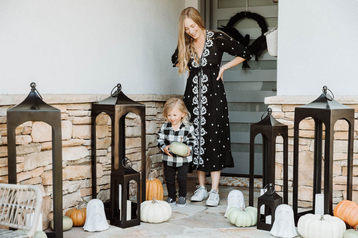 Toddler holding faux pumpkin and Fall & Halloween Decor For Patio & Yard with Lanterns, faux pumpkins, crow wreath and LED ghosts