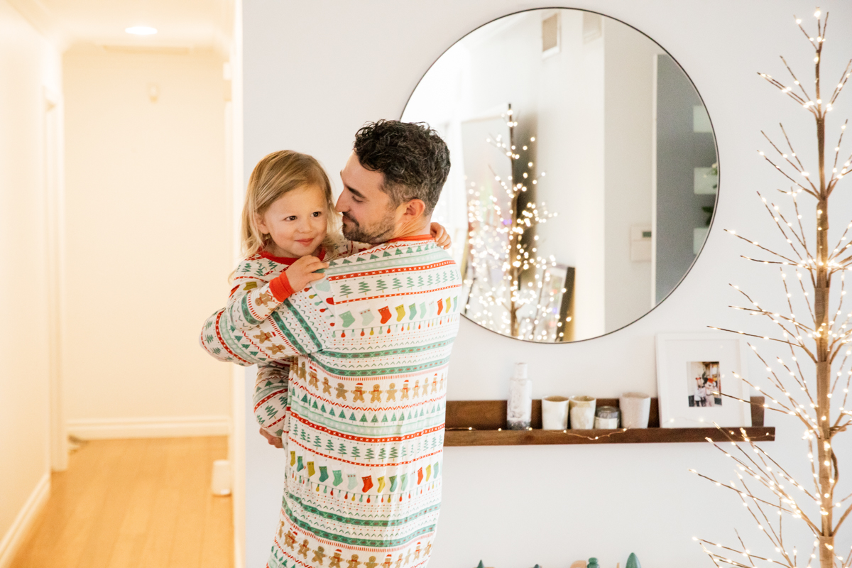 Indoor Holiday decor of twinkle lights tree, twinkle lights, and father and son in Christmas pajamas