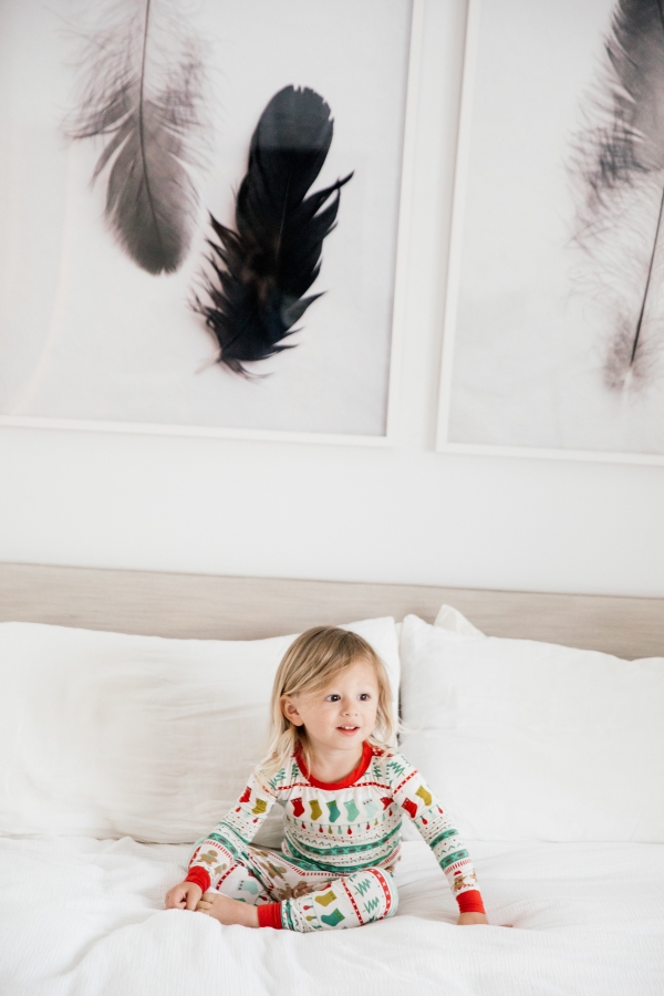 Toddler in Holiday pajamas laughing on the bed