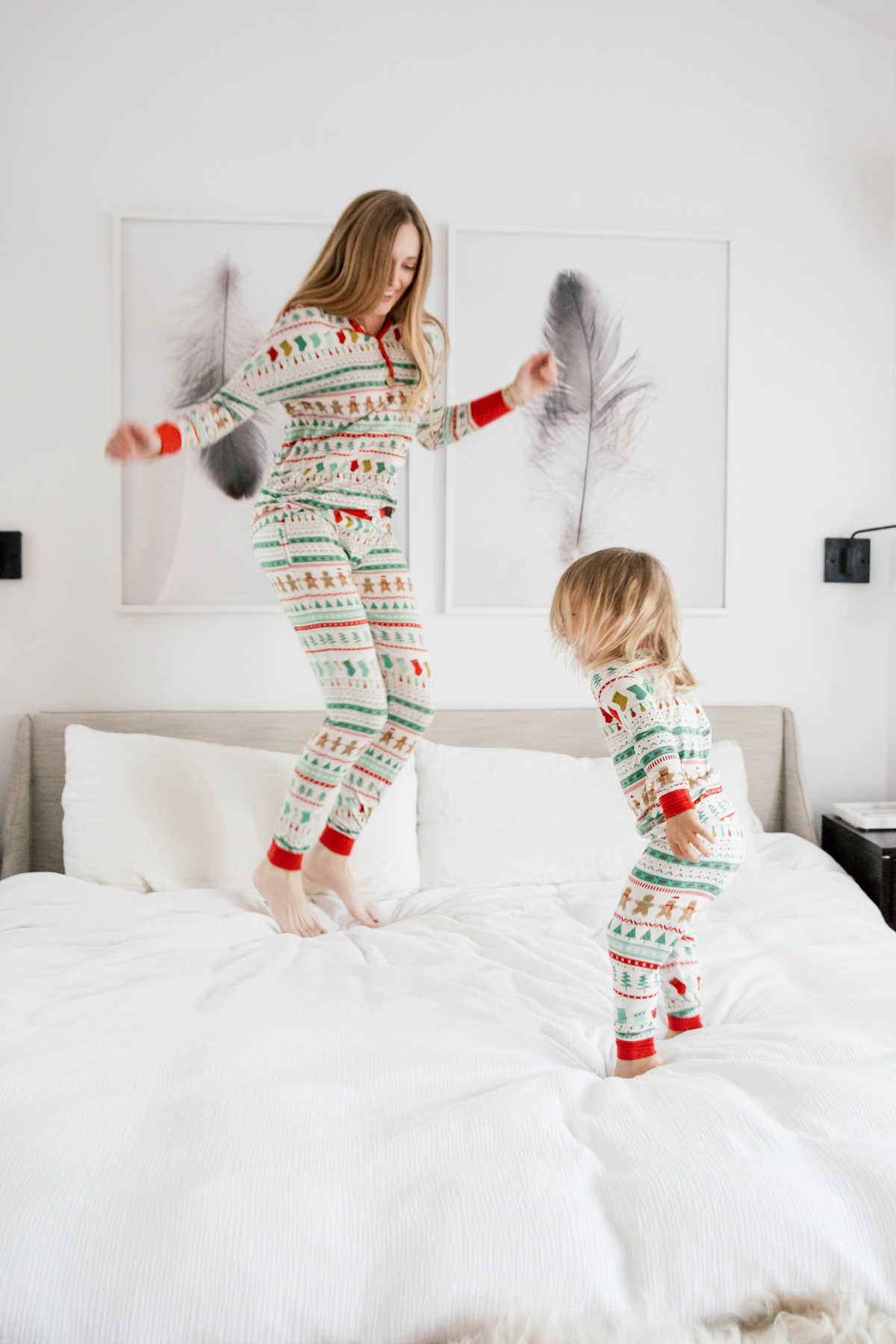 Mother and son in matching Holiday pajamas jumping on the bed